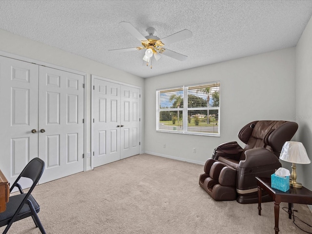 sitting room featuring light carpet, a textured ceiling, and ceiling fan