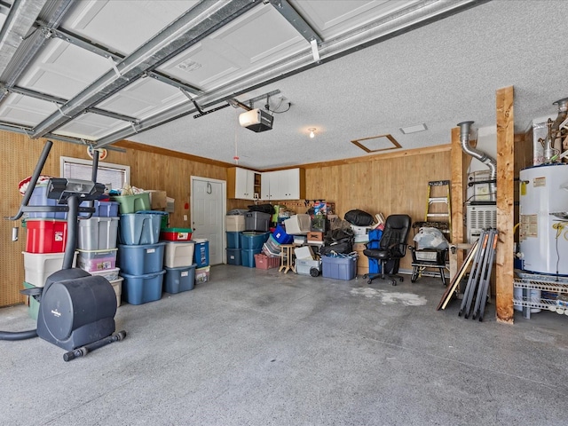 garage with a garage door opener, wood walls, and water heater