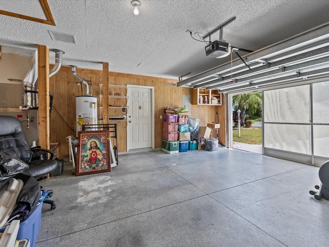 garage featuring a garage door opener, wooden walls, and gas water heater