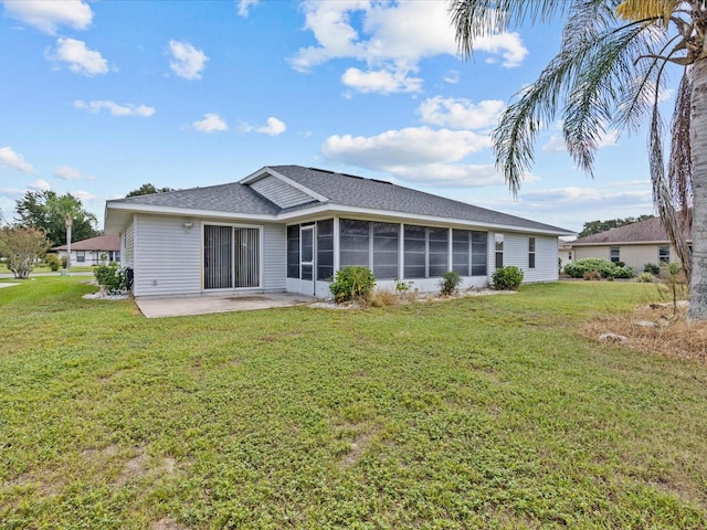 rear view of house with a yard, a patio area, and a sunroom