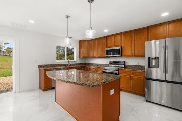 kitchen featuring sink, a kitchen island, stainless steel appliances, pendant lighting, and dark stone countertops