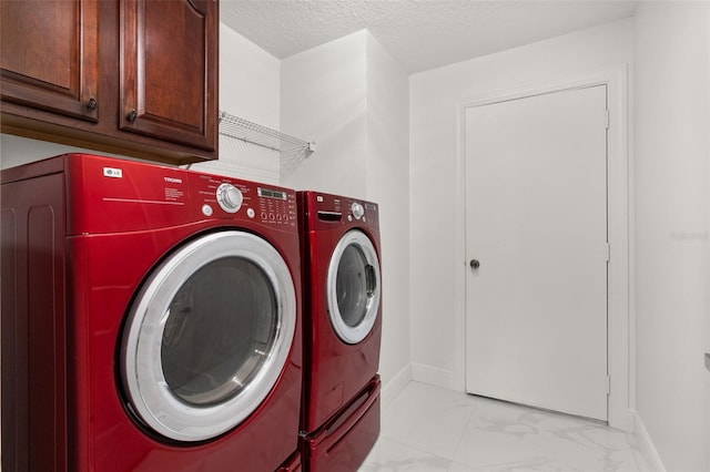 washroom with a textured ceiling, washing machine and clothes dryer, and cabinets