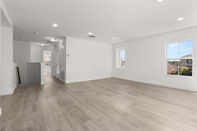 spare room featuring a textured ceiling and light wood-type flooring