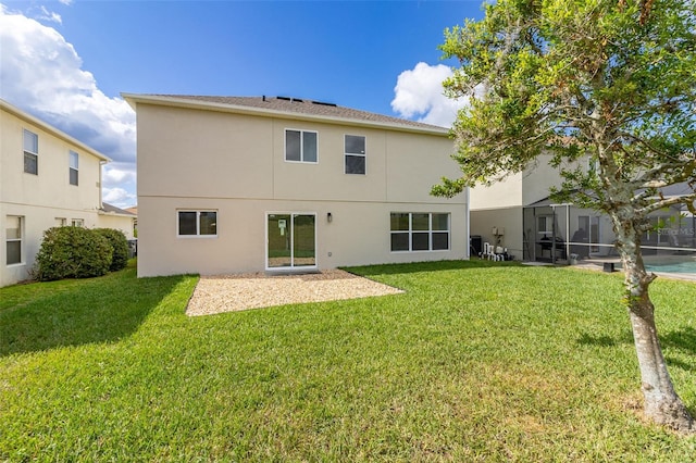 rear view of property featuring a lawn and glass enclosure