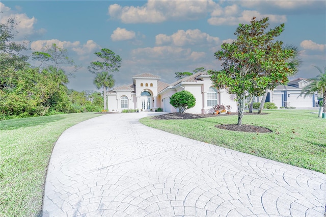 mediterranean / spanish-style house featuring a front yard and a garage