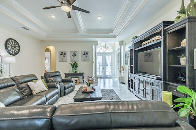 living room with crown molding, a tray ceiling, french doors, and ceiling fan