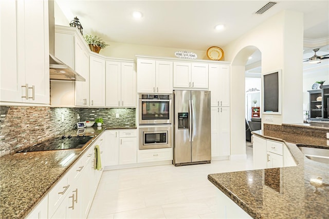 kitchen featuring white cabinetry, backsplash, stainless steel appliances, and dark stone counters