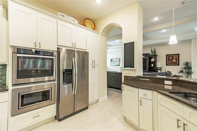 kitchen with hanging light fixtures, white cabinetry, stainless steel appliances, dark stone countertops, and light tile patterned floors