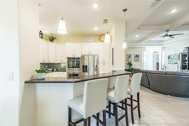 kitchen featuring coffered ceiling, hanging light fixtures, a breakfast bar, white cabinets, and appliances with stainless steel finishes