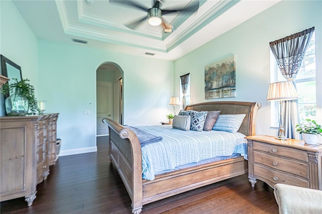 bedroom featuring dark wood-type flooring, ceiling fan, a raised ceiling, and ornamental molding