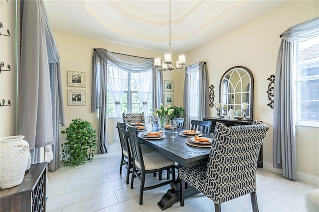 dining area with an inviting chandelier, a raised ceiling, and crown molding