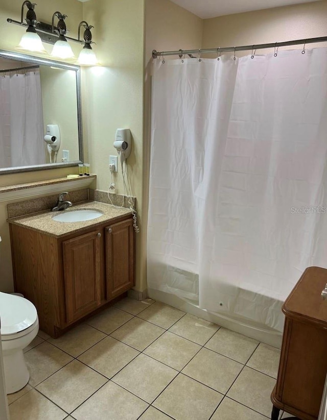 full bathroom with toilet, shower / bath combo with shower curtain, vanity, and tile patterned flooring