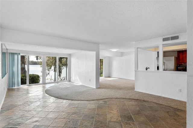 carpeted spare room with french doors and a textured ceiling