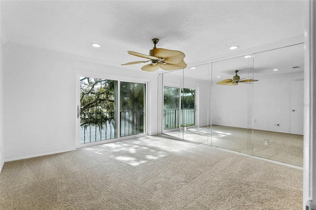 carpeted empty room featuring a textured ceiling, ceiling fan, and plenty of natural light