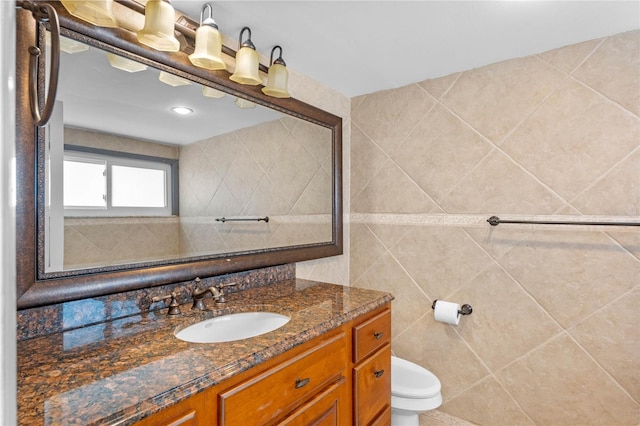 bathroom with tile walls, tile patterned flooring, vanity, and toilet