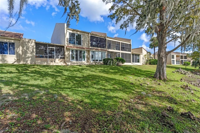 back of house featuring a lawn and a sunroom