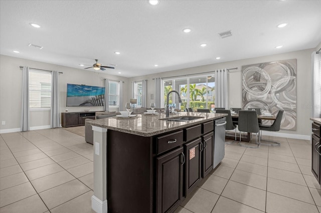 kitchen with a kitchen island with sink, sink, ceiling fan, light tile patterned floors, and light stone counters