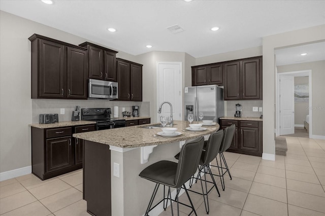 365 Southfield St, Kissimmee, FL 34747 - kitchen featuring stainless steel appliances, light tile patterned flooring, a breakfast bar, decorative backsplash, and dark brown cabinets