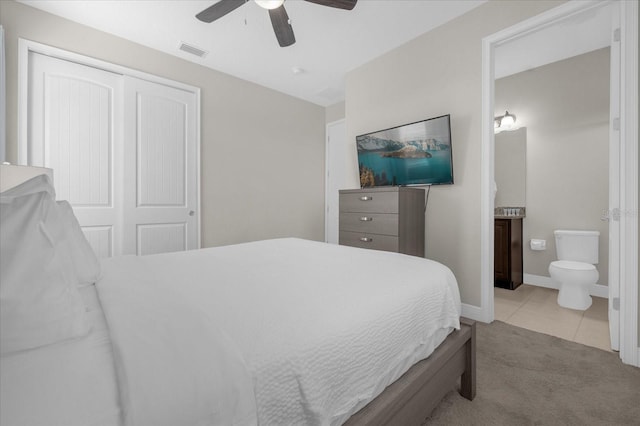 bedroom featuring ceiling fan, light carpet, connected bathroom, and a closet