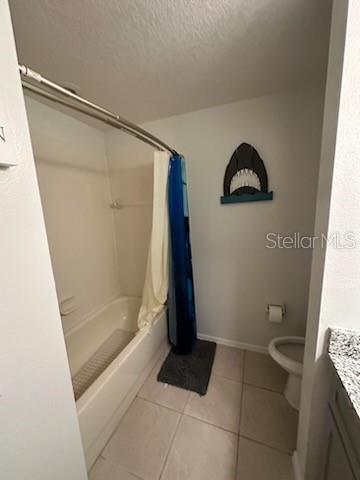 full bathroom with shower / tub combo, a textured ceiling, toilet, tile patterned floors, and vanity