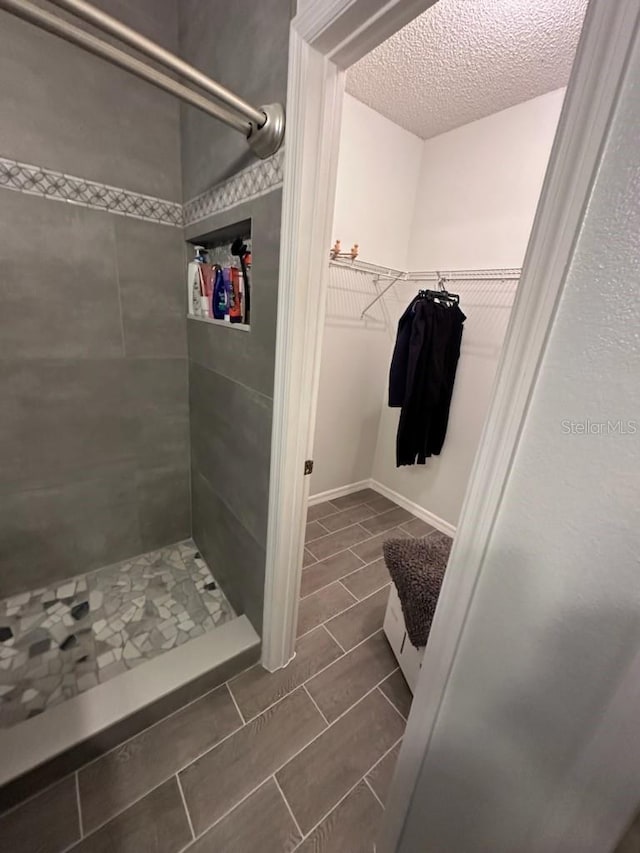 bathroom featuring a textured ceiling and tiled shower