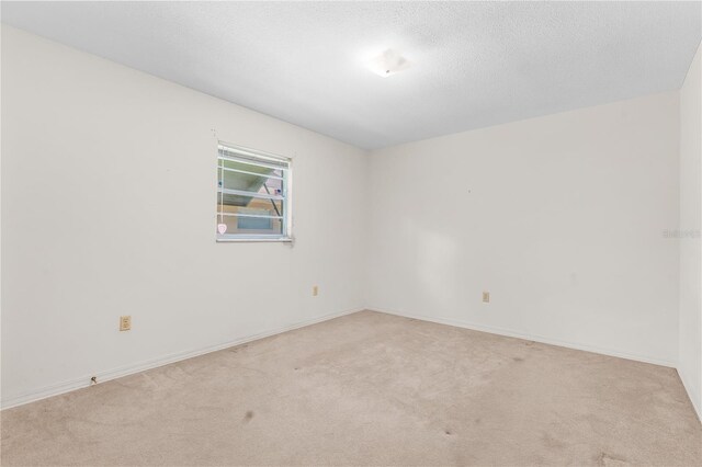 spare room featuring light colored carpet and a textured ceiling