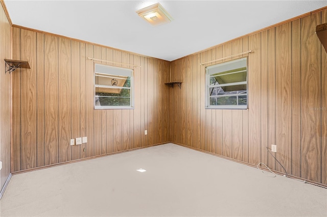 carpeted spare room featuring wood walls