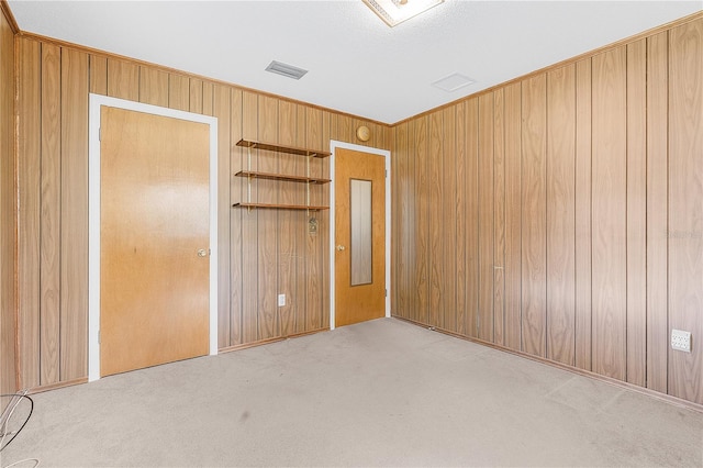 unfurnished bedroom with a closet, light colored carpet, and wood walls