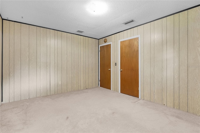 spare room featuring wooden walls, a textured ceiling, and carpet flooring