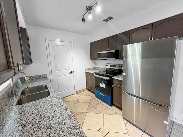 kitchen featuring stainless steel appliances, dark brown cabinetry, sink, and light tile patterned flooring