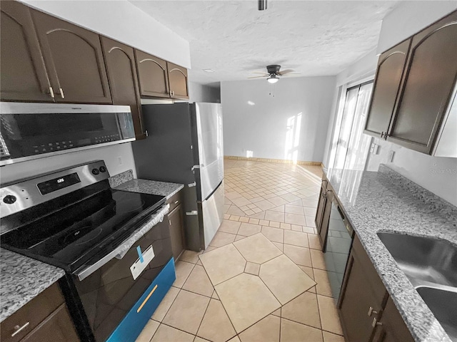 kitchen featuring light stone countertops, appliances with stainless steel finishes, sink, dark brown cabinetry, and light tile patterned floors