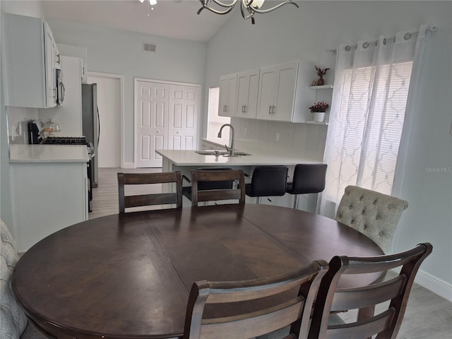 dining room with lofted ceiling, sink, and light hardwood / wood-style flooring