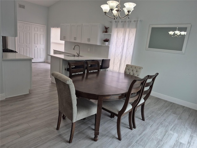 dining room featuring light hardwood / wood-style flooring, a notable chandelier, sink, and lofted ceiling