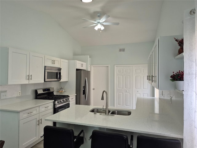 kitchen with sink, kitchen peninsula, appliances with stainless steel finishes, a kitchen bar, and white cabinets