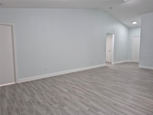 empty room featuring light wood-type flooring and lofted ceiling