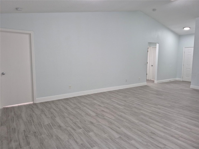 spare room with light hardwood / wood-style floors and lofted ceiling