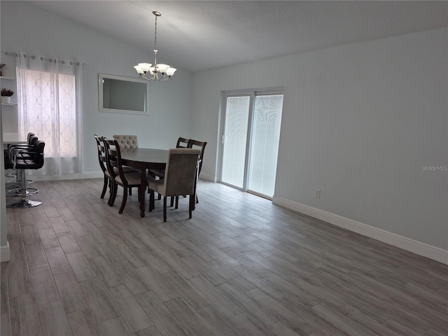 dining area with hardwood / wood-style floors, a textured ceiling, an inviting chandelier, and vaulted ceiling