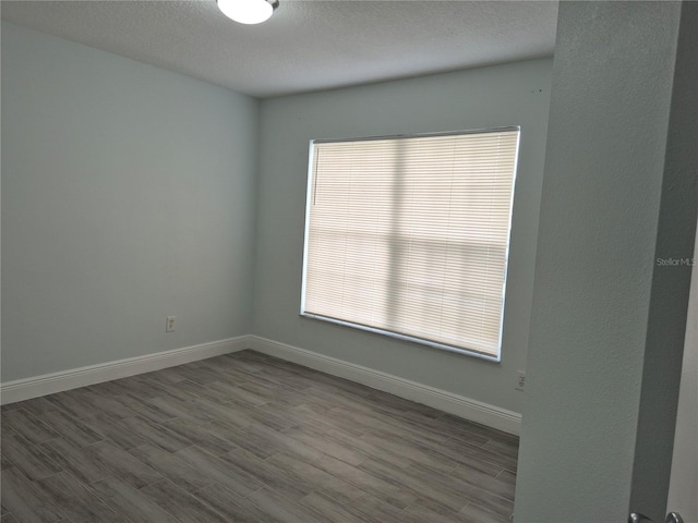 spare room with light hardwood / wood-style floors and a textured ceiling