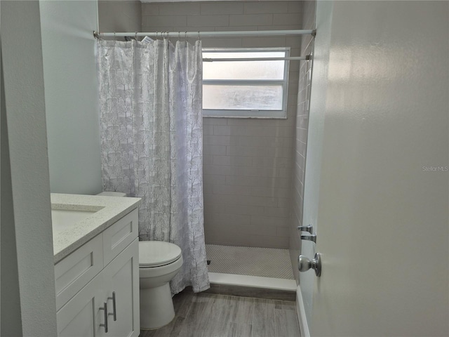 bathroom featuring toilet, vanity, hardwood / wood-style flooring, and walk in shower