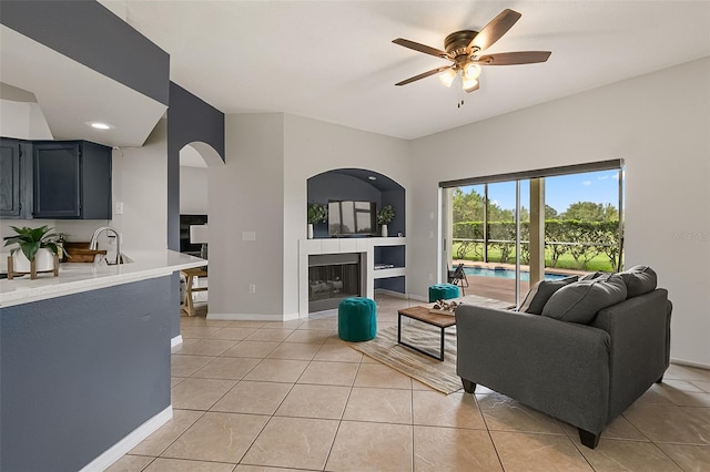 living room featuring ceiling fan, sink, and light tile patterned floors