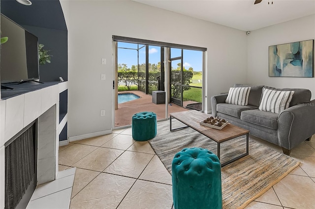 living room featuring ceiling fan, a fireplace, and tile patterned flooring