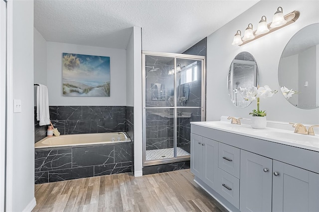 bathroom featuring wood-type flooring, separate shower and tub, a textured ceiling, and vanity