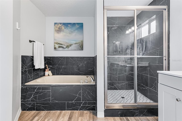 bathroom featuring vanity, hardwood / wood-style floors, a textured ceiling, and plus walk in shower