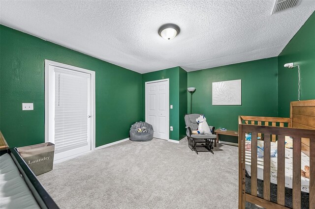 carpeted bedroom with a closet, a nursery area, and a textured ceiling