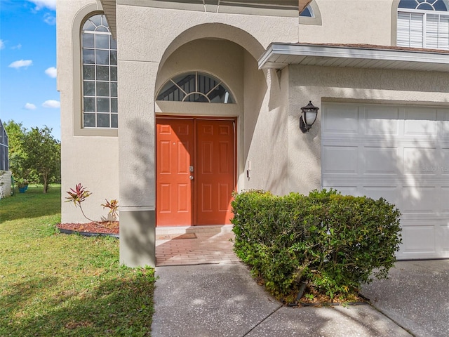 entrance to property featuring a garage and a lawn