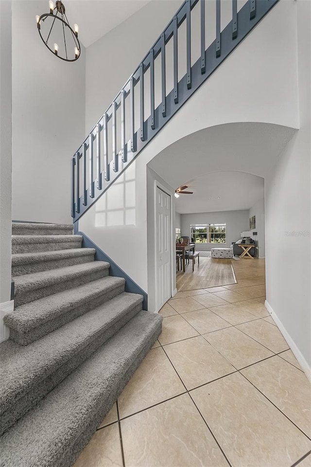 stairway with an inviting chandelier and tile patterned flooring