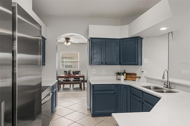 kitchen featuring sink, blue cabinetry, stainless steel fridge, and ceiling fan