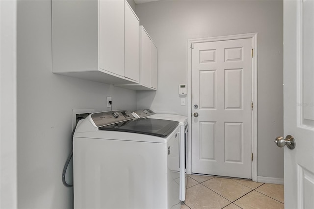 clothes washing area with independent washer and dryer, cabinets, and light tile patterned floors