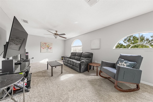 carpeted living room with ceiling fan and a textured ceiling