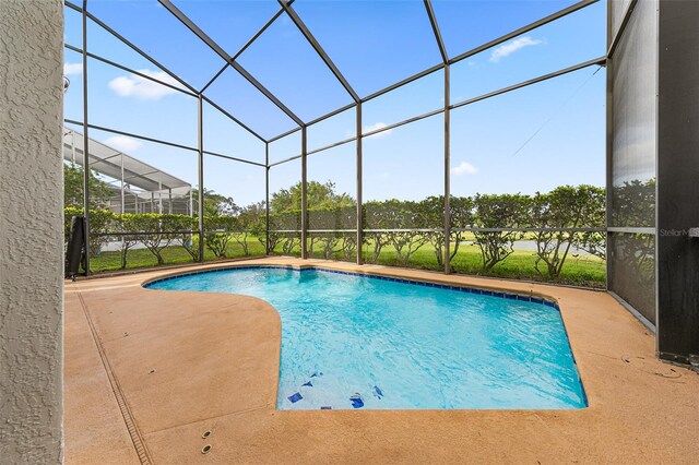 view of swimming pool featuring glass enclosure and a patio